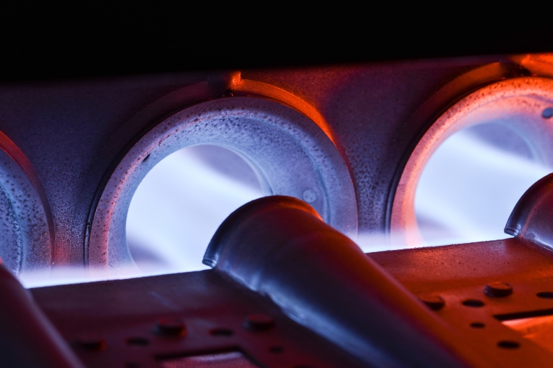 It is Time to Tune Up Your Heating System. Closeup Shot Of Home Furnace Burner Ignited With Crimson Blue Flame.