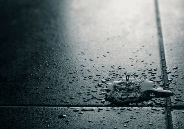 close up still of water droplets hitting the ground.