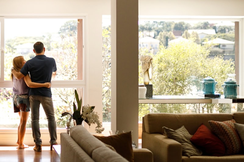 5 Tips for Extending the Lifespan of Your HVAC System. Photo of a young couple admiring the view from their living room window.