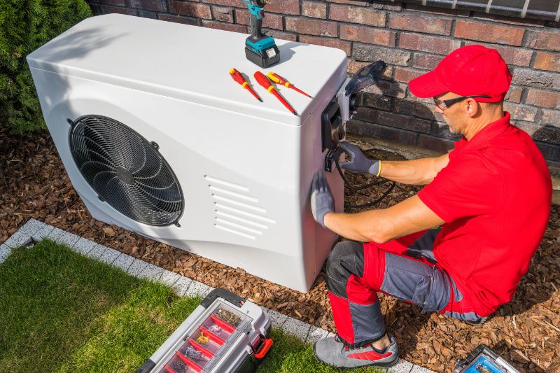 Image of technician working on heat pump. 4 Factors to Consider When Buying a Heat Pump.